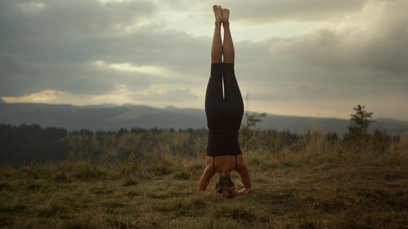 A woman performing a headstand balance pose, which helps strengthen the entire body